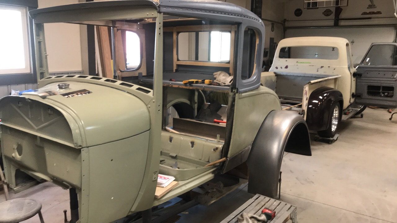 Two old cars are being restored in a garage.