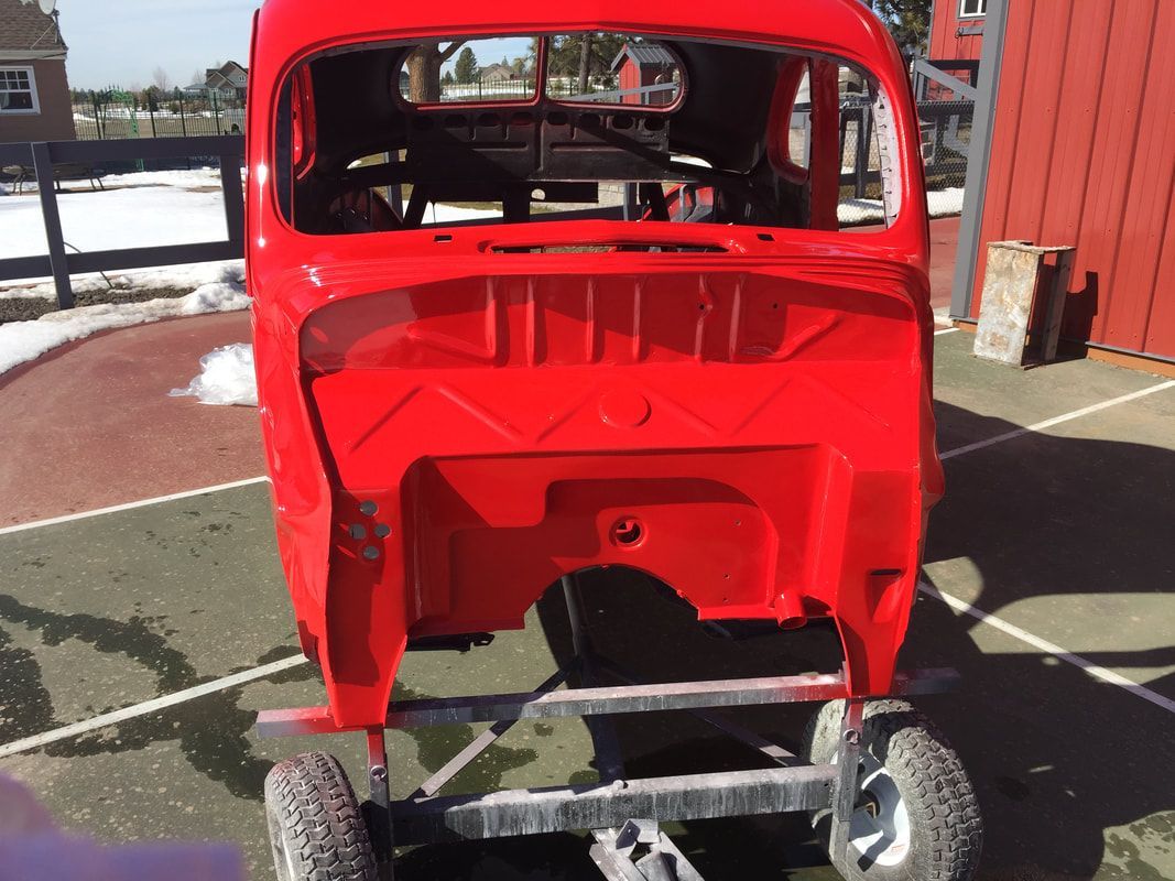 A red car is parked in front of a red building.