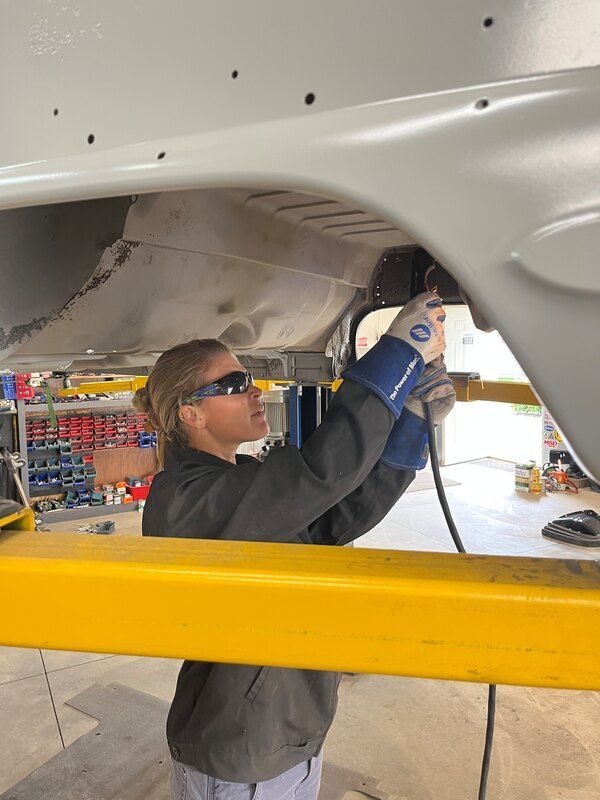 A woman is working on a car in a garage.