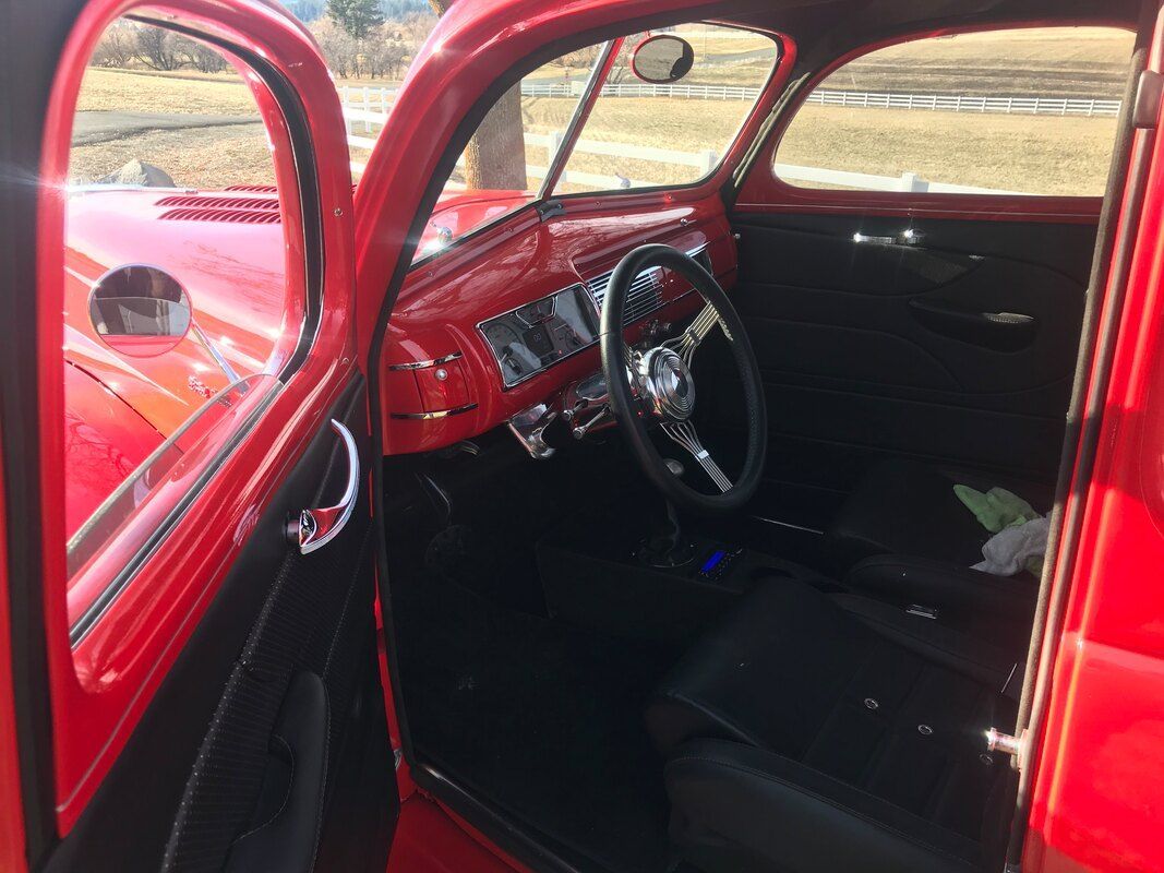 The interior of a red car with black seats and a steering wheel.