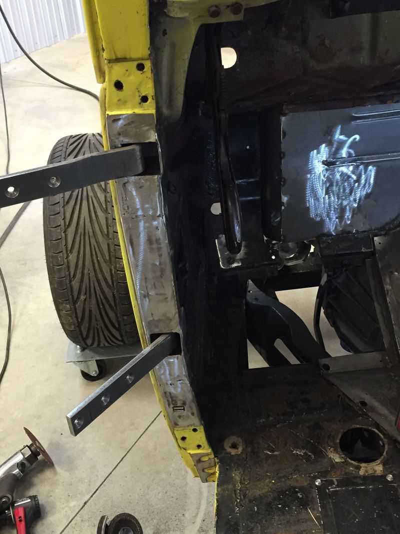 A yellow car is being worked on in a garage