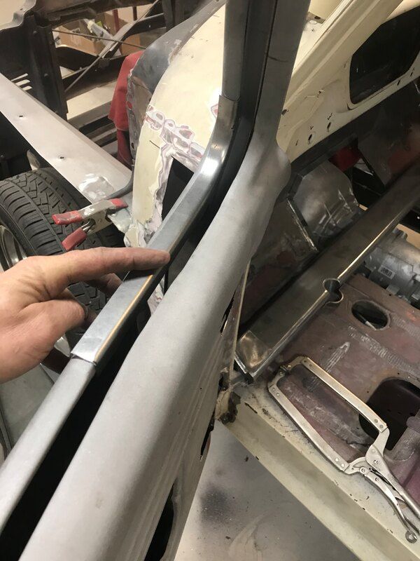 A person is pointing at a piece of metal on a car.