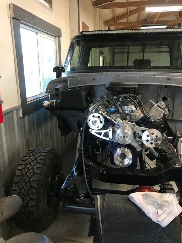 A truck is being built in a garage and the engine is visible.
