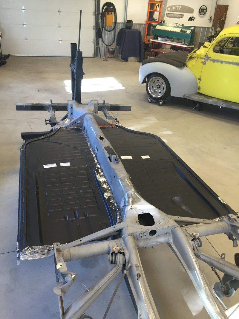 A yellow car is parked in a garage next to a metal frame