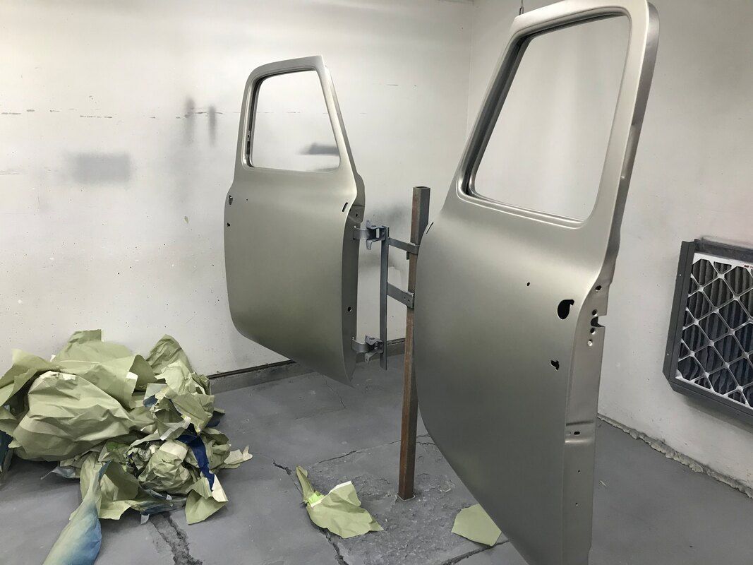 Two doors are being painted in a paint booth.