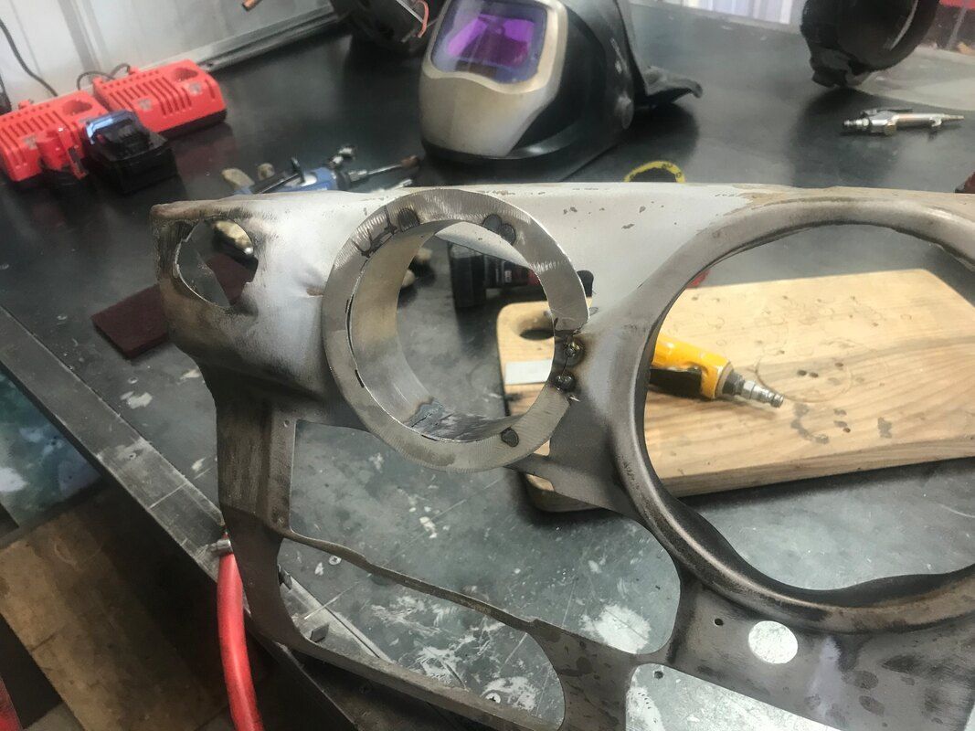 A piece of metal is sitting on a table next to a welding helmet.