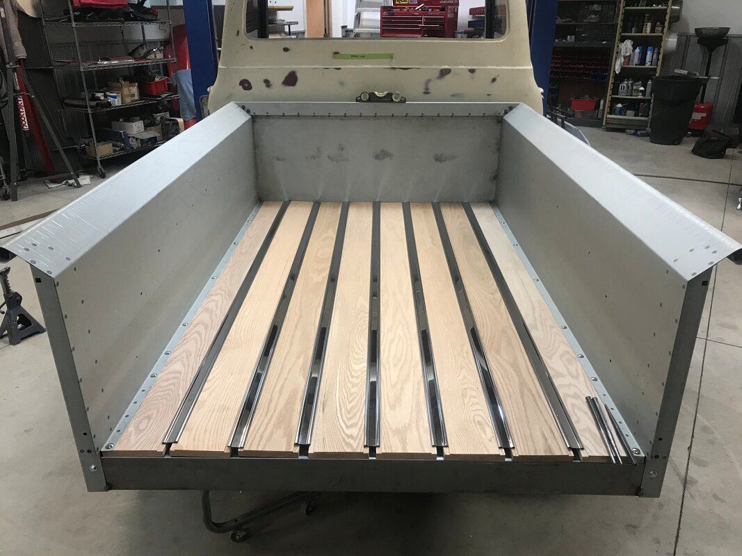 A truck with a wooden bed is sitting in a garage.