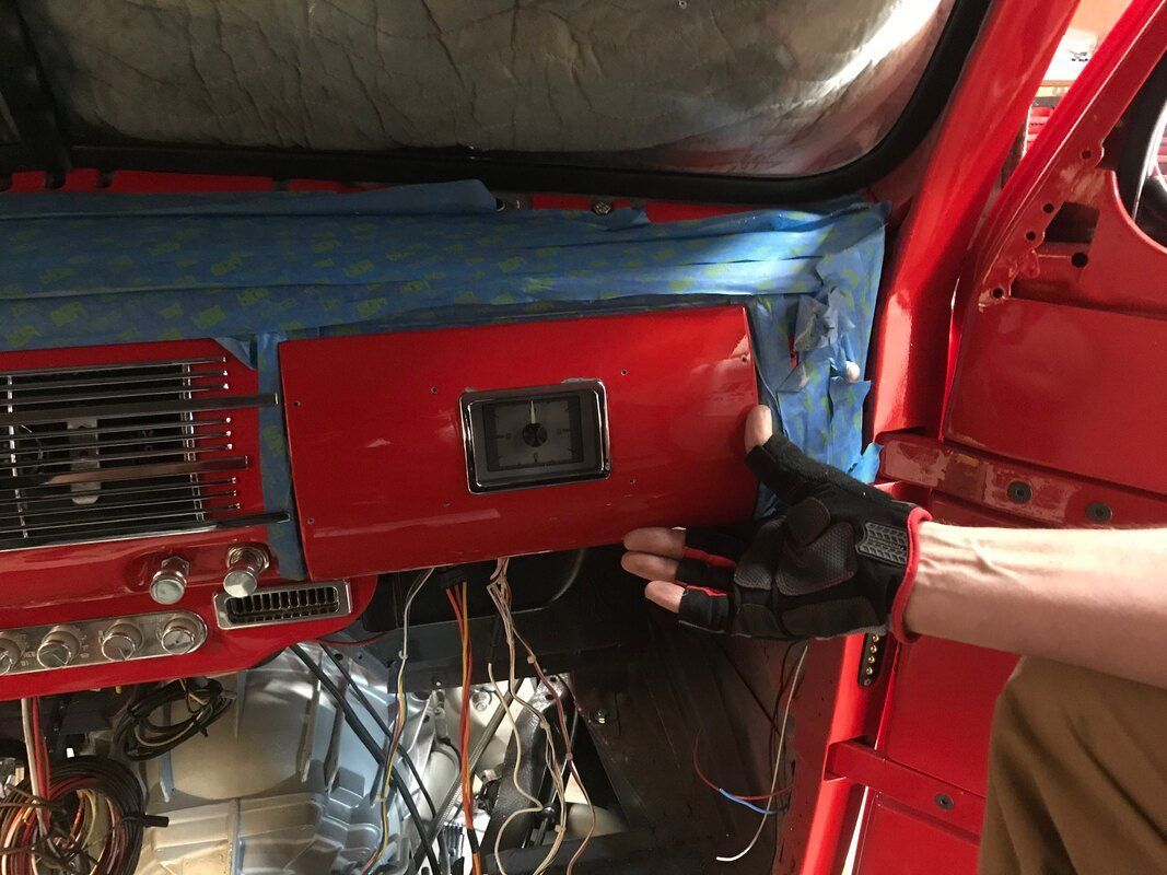 A person is working on the dashboard of a red car.