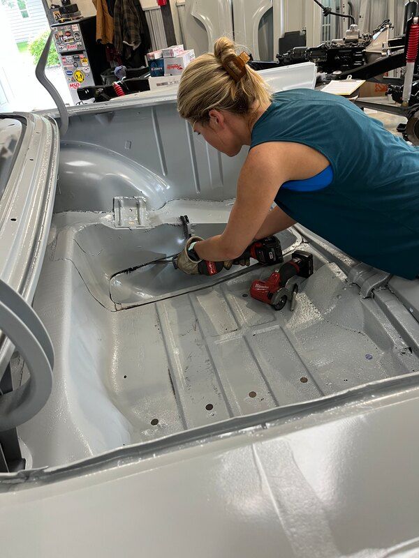 A woman is working on the back of a car.