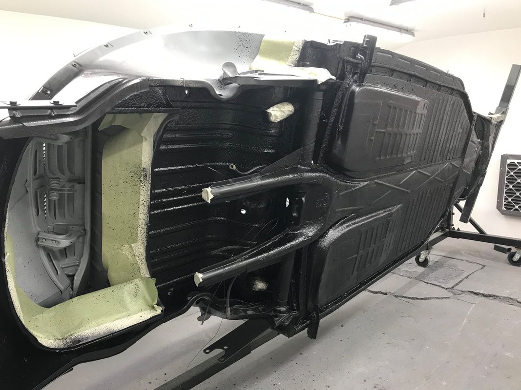 A yellow beetle is being built in a garage.