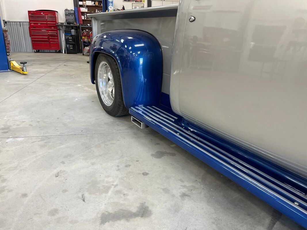 A silver and blue truck is parked in a garage.
