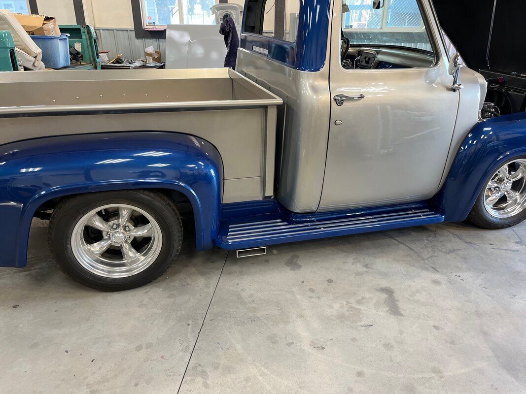 A blue and silver truck is parked in a garage.