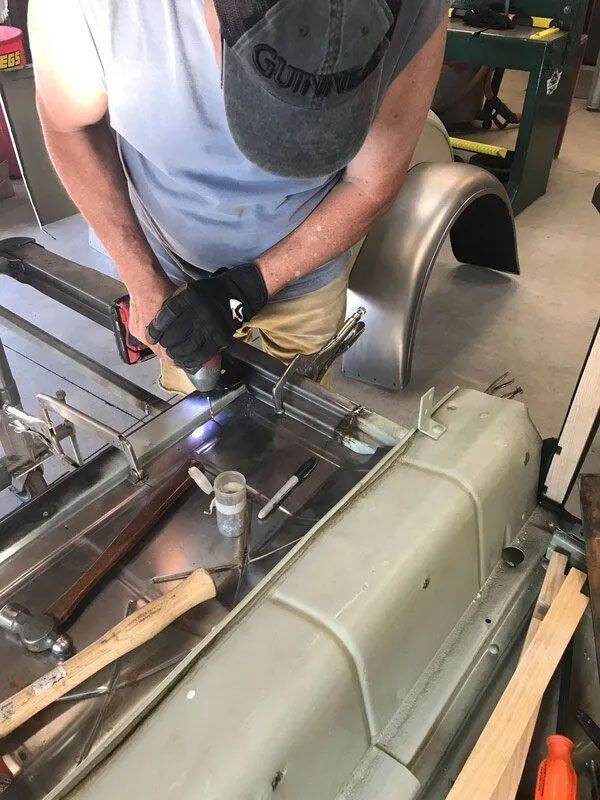 A man is working on a piece of metal in a garage.