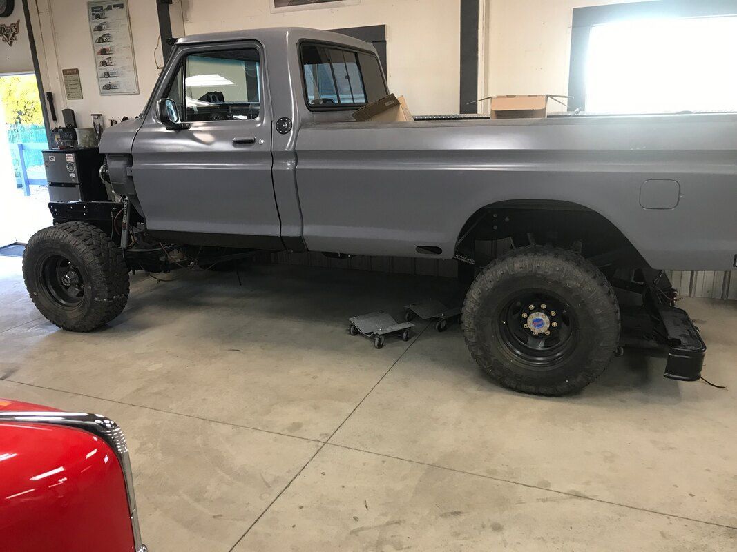 A gray truck is parked in a garage next to a red car.