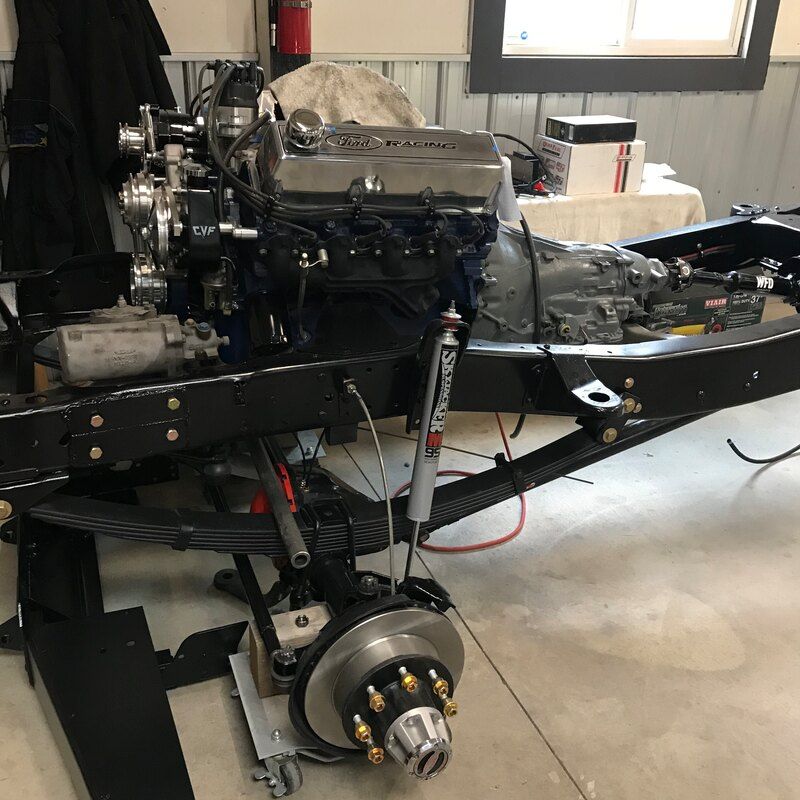 A car engine is sitting on top of a frame in a garage.