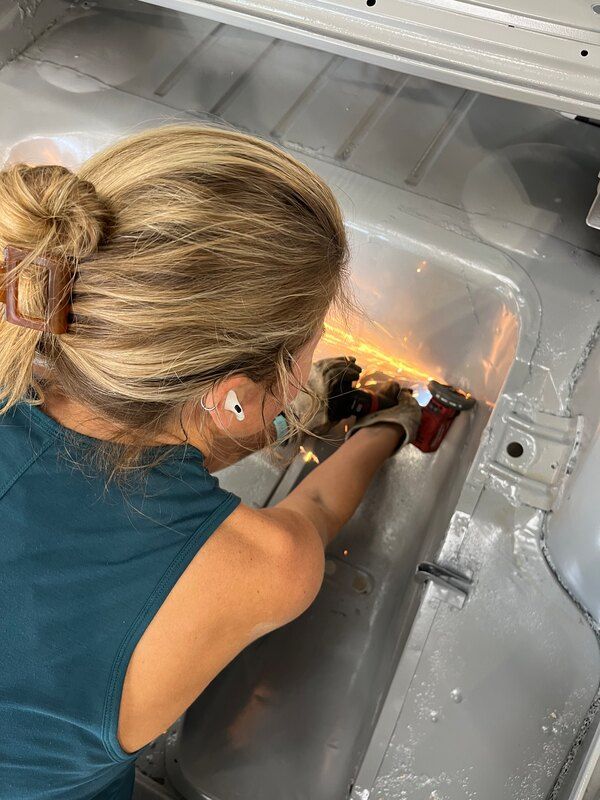 A woman is working on the inside of a refrigerator.