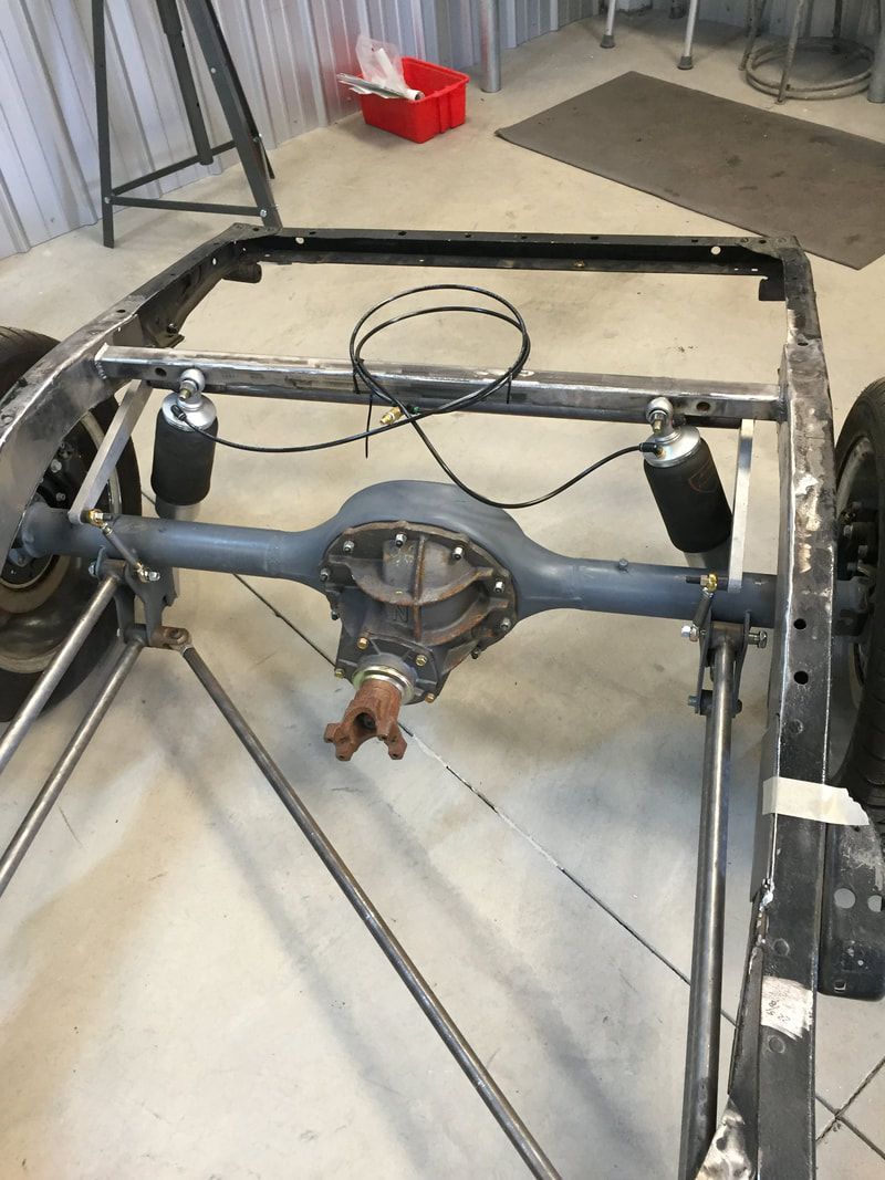 The rear end of a car is being built in a garage.