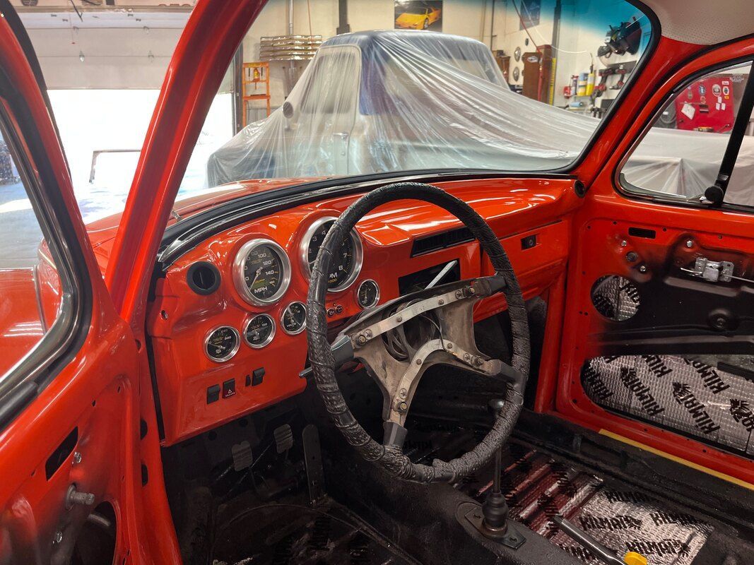 The inside of an orange car with a steering wheel and dashboard