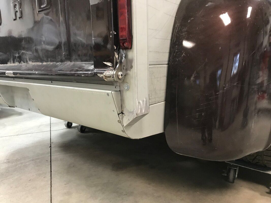 A white truck with a brown fender is parked in a garage.
