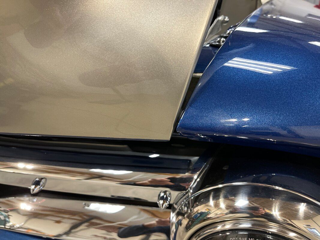 A close up of a blue motorcycle with a chrome exhaust pipe