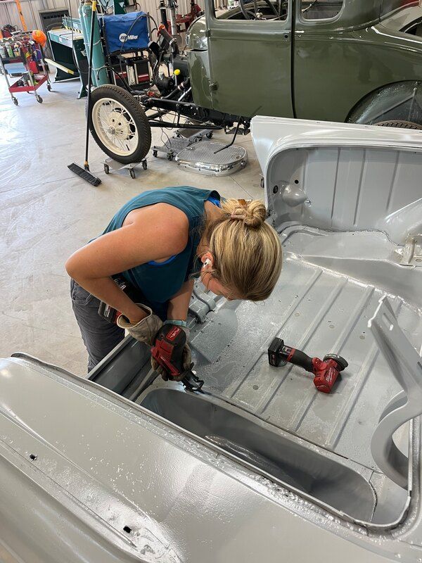 A woman is working on a car in a garage.