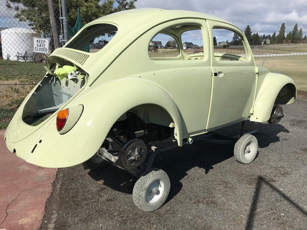 A yellow beetle with wheels is parked on the side of the road.