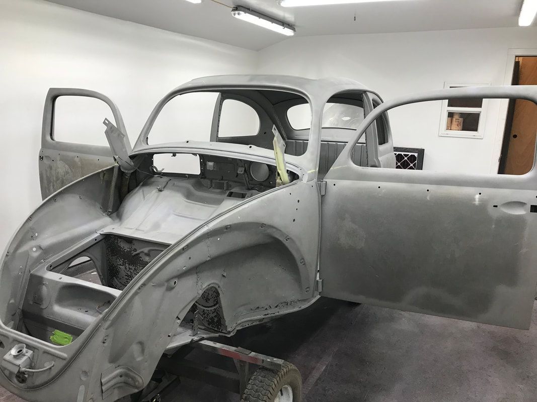 A car is sitting in a garage with its doors open.