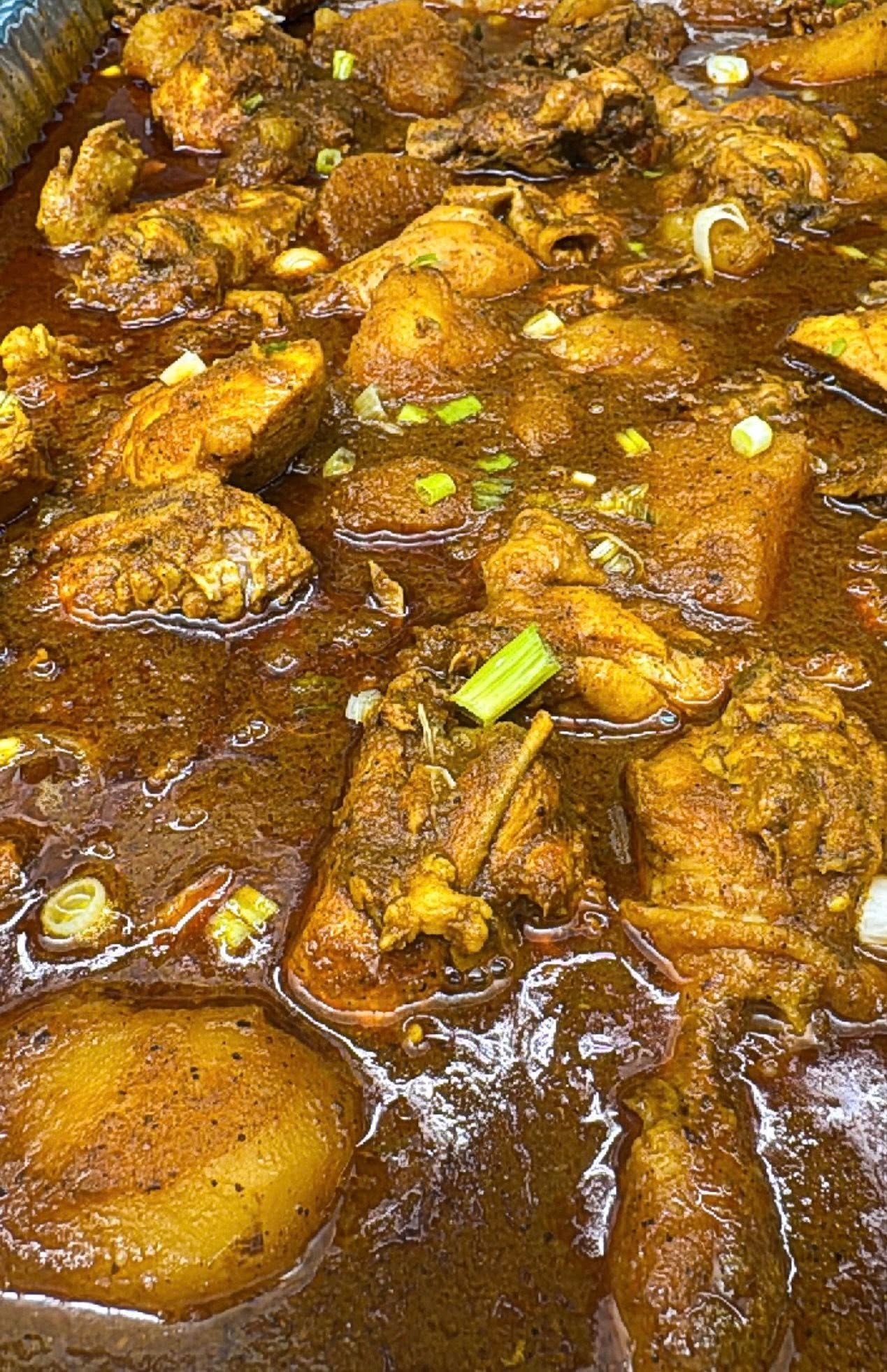 Curried chicken and potatoes in a rich, brown sauce, garnished with green onions.