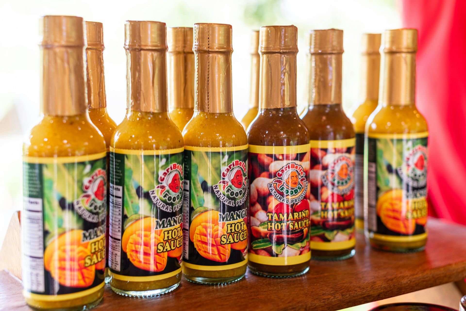 Bottles of tropical-flavored hot sauce on display with gold caps and colorful labels.