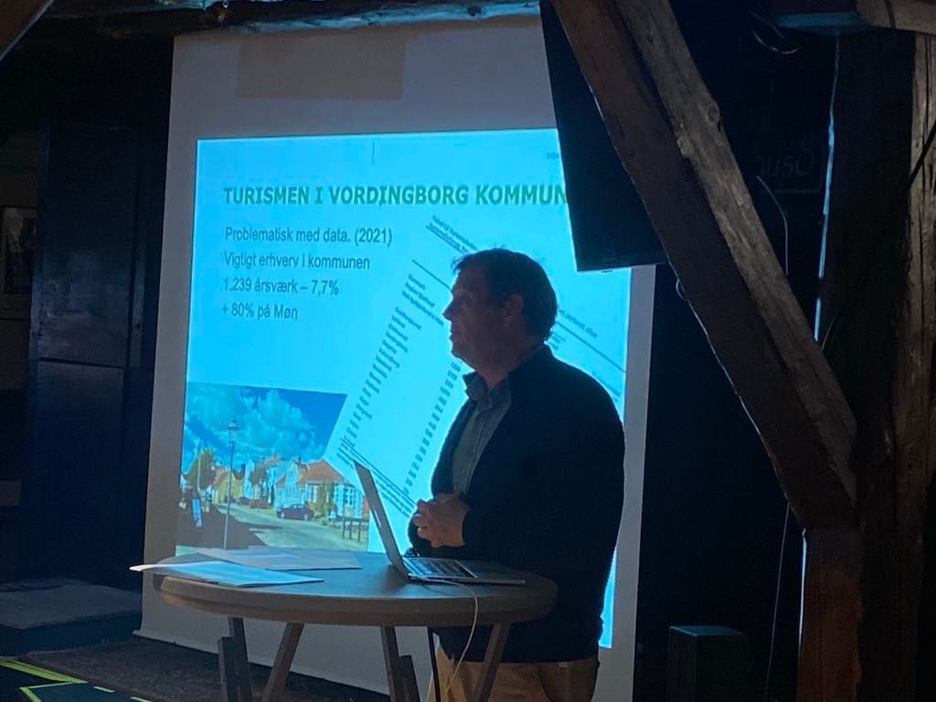 En mand holder en præsentation foran et projektorlærred.