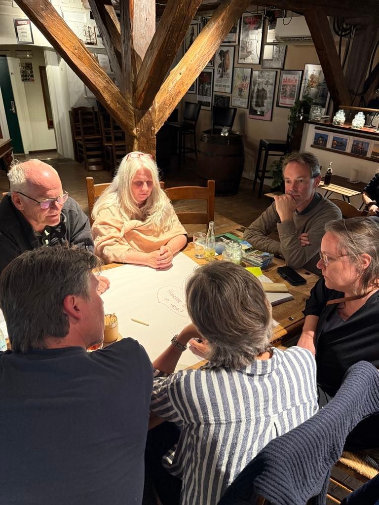 En gruppe mennesker sidder omkring et bord og snakker.