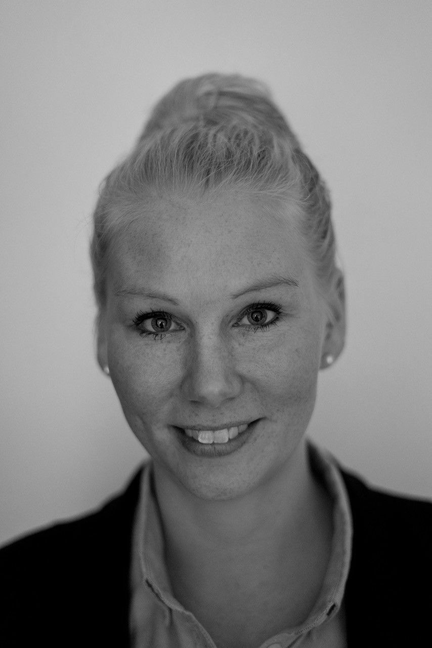 Sort- hvidt billede af Ditte. Hun har håret samlet, stort smil og ørenringe.