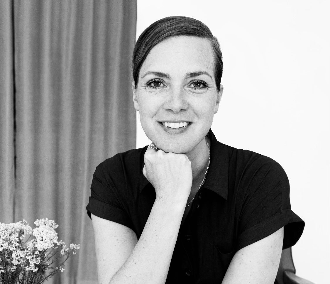 Sort-hvidt billede af Anna. Hun holder hånden under hagen. Der er et gardin i baggrunden.