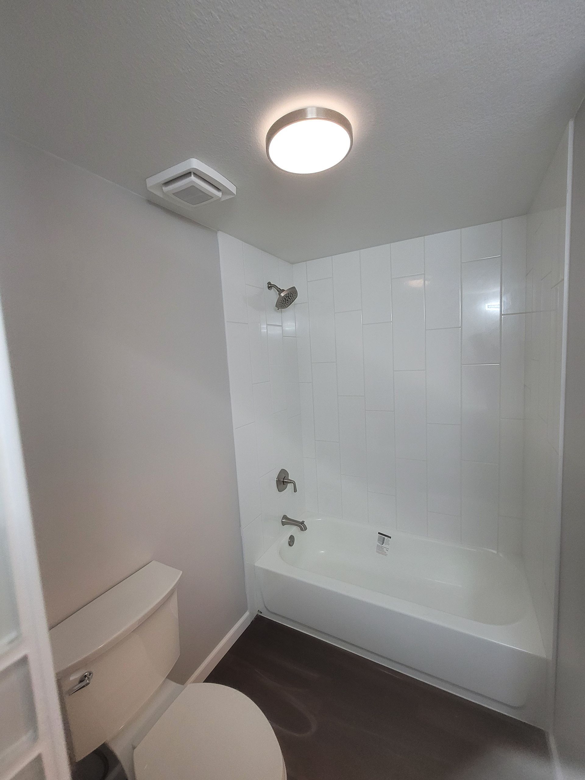 A bathroom with a toilet , bathtub and shower.