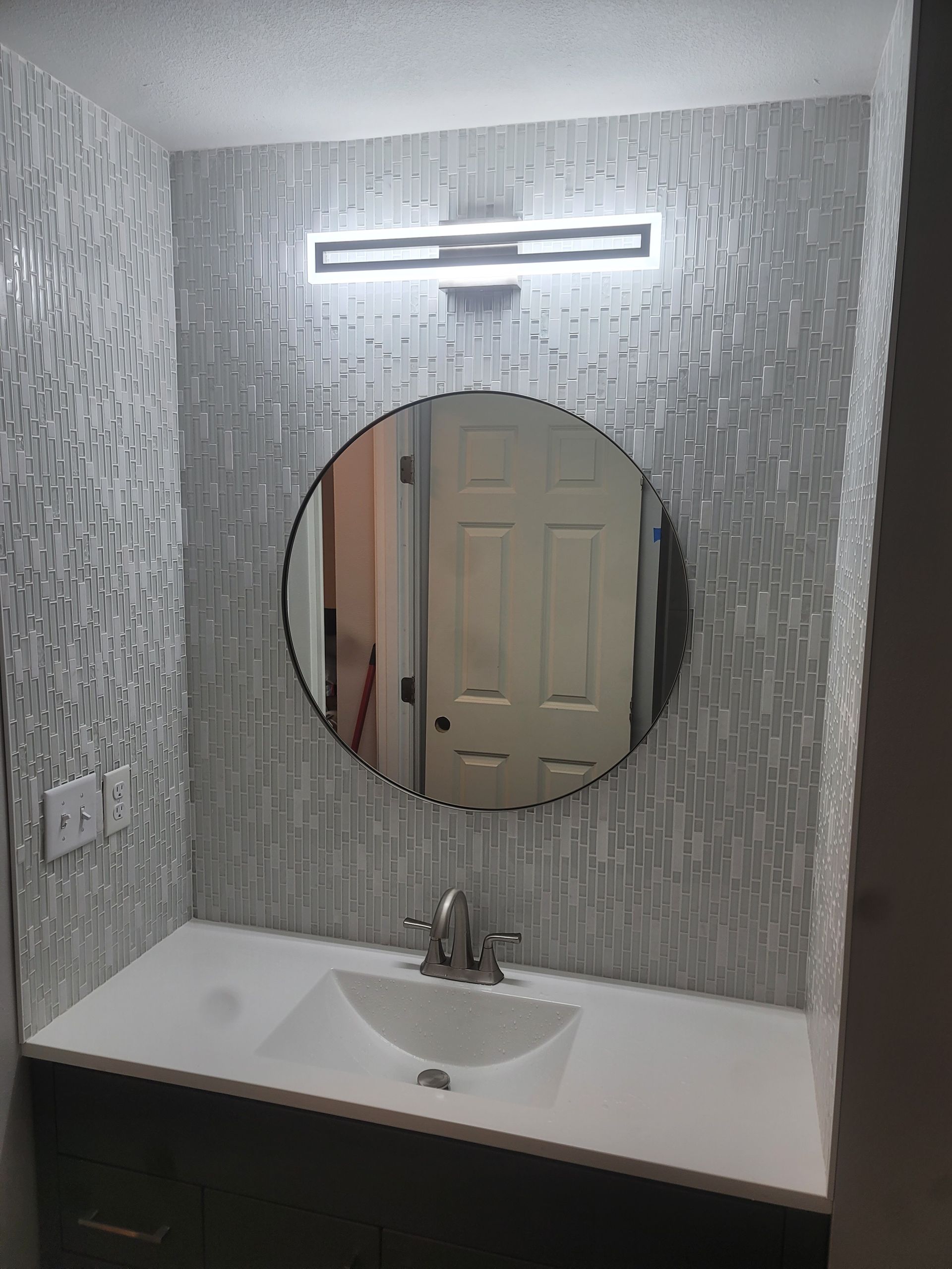 A bathroom with a sink , mirror and light.