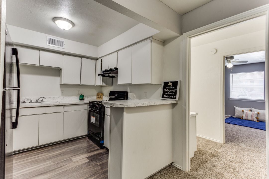 A kitchen with white cabinets , a refrigerator , a stove , and a sink.