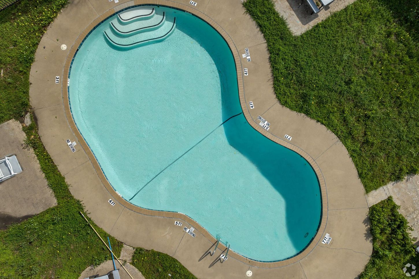 An aerial view of a large swimming pool surrounded by grass.