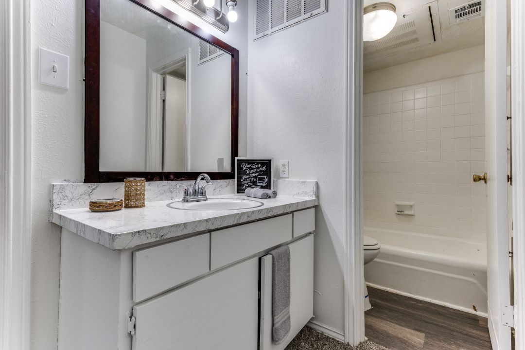 A bathroom with a sink , mirror and tub.