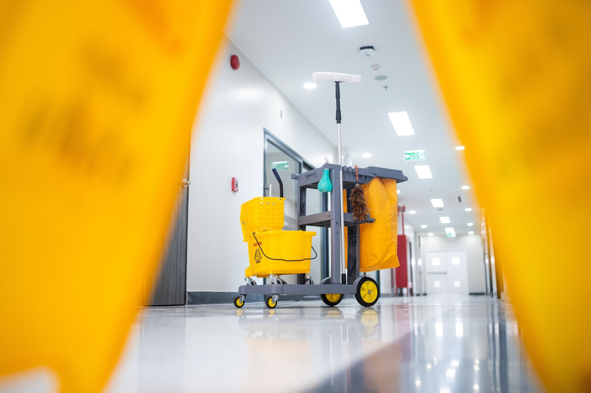 A janitorial cart with a yellow mop bucket.