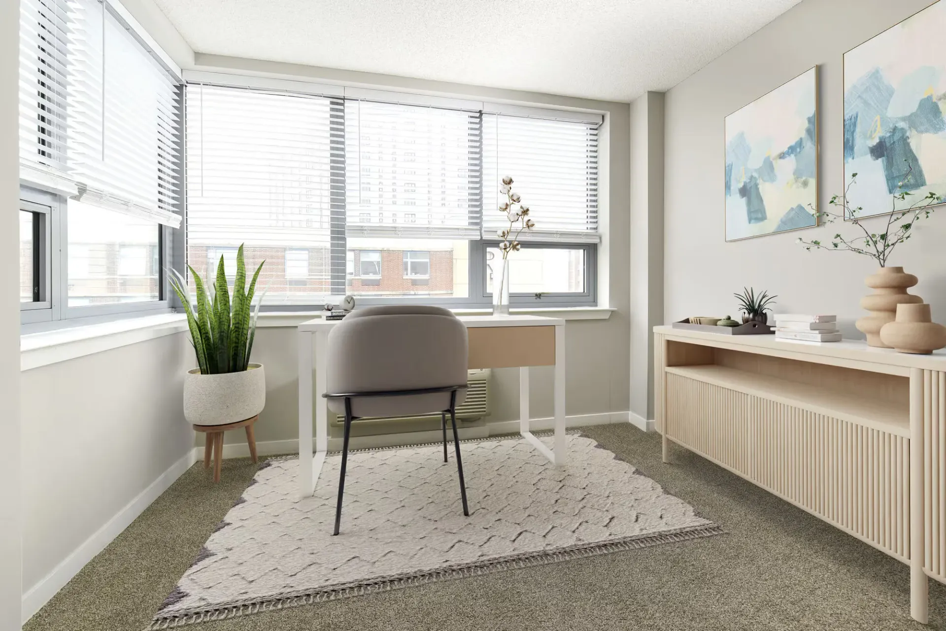 Bright apartment office with large windows, blinds, desk, chair, and plant.