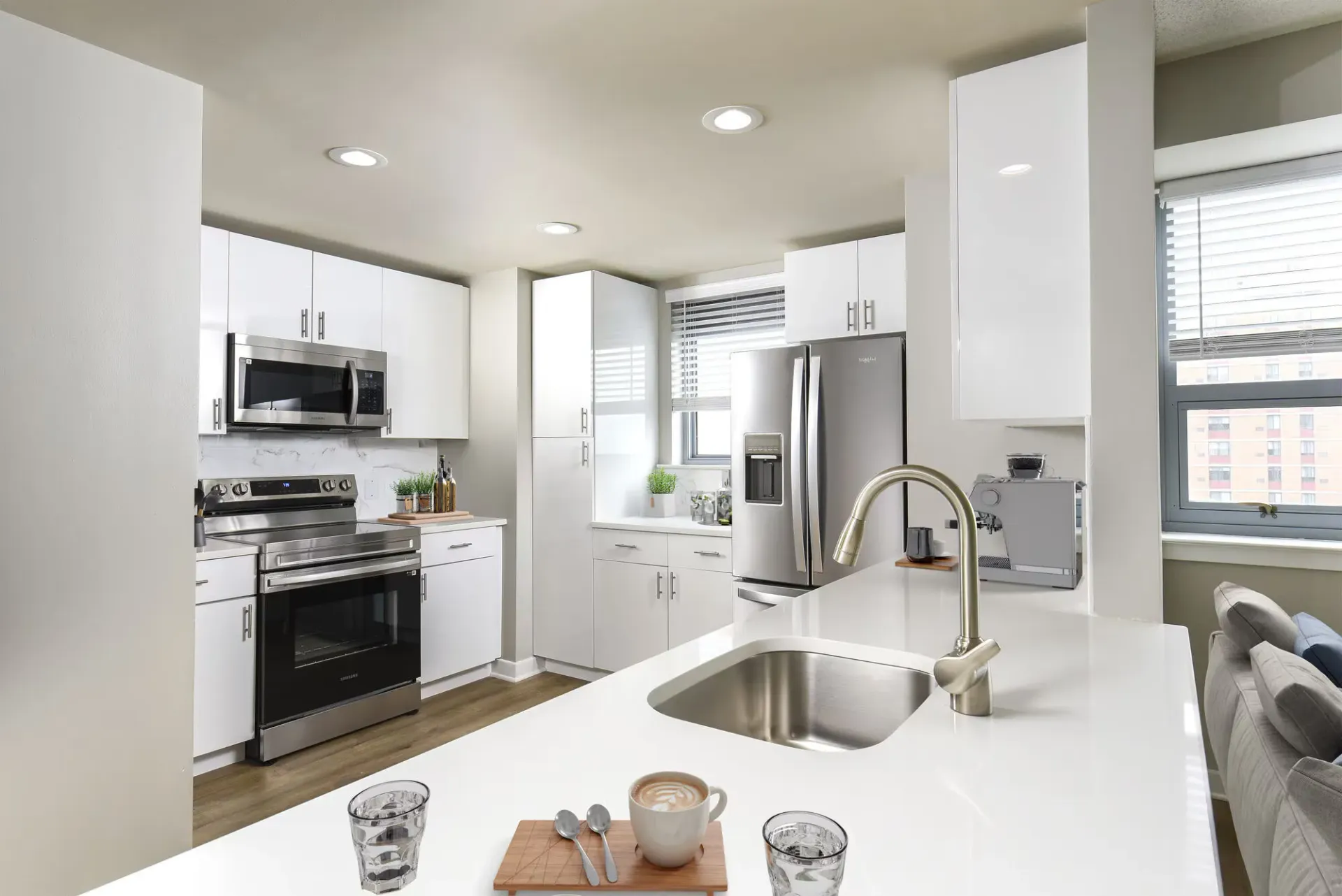 Modern white kitchen with stainless steel appliances and an island.