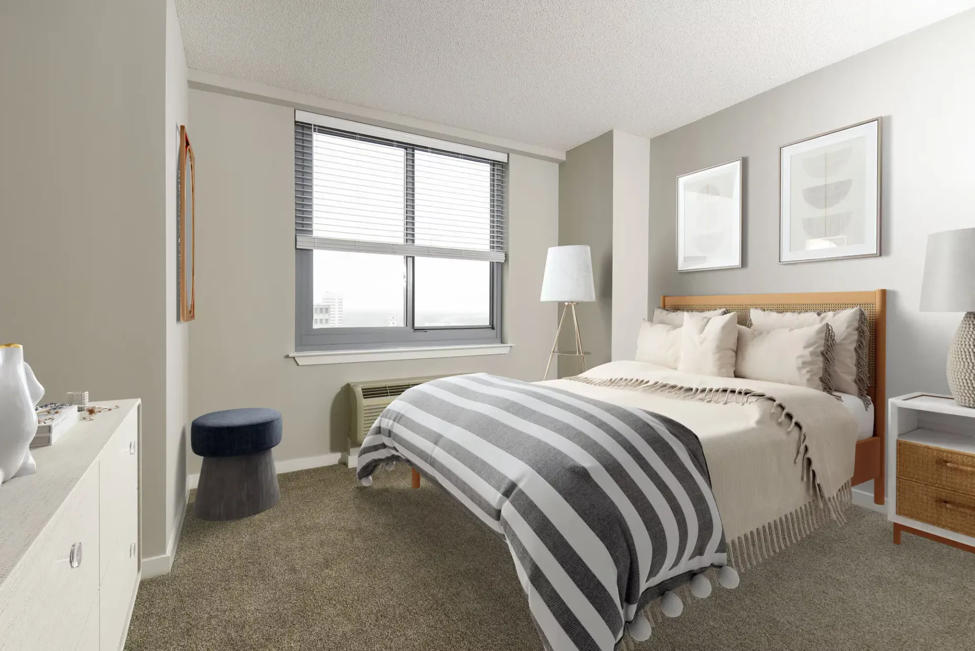 Bedroom in a furnished apartment with a bed, nightstands, dresser, and a large window.