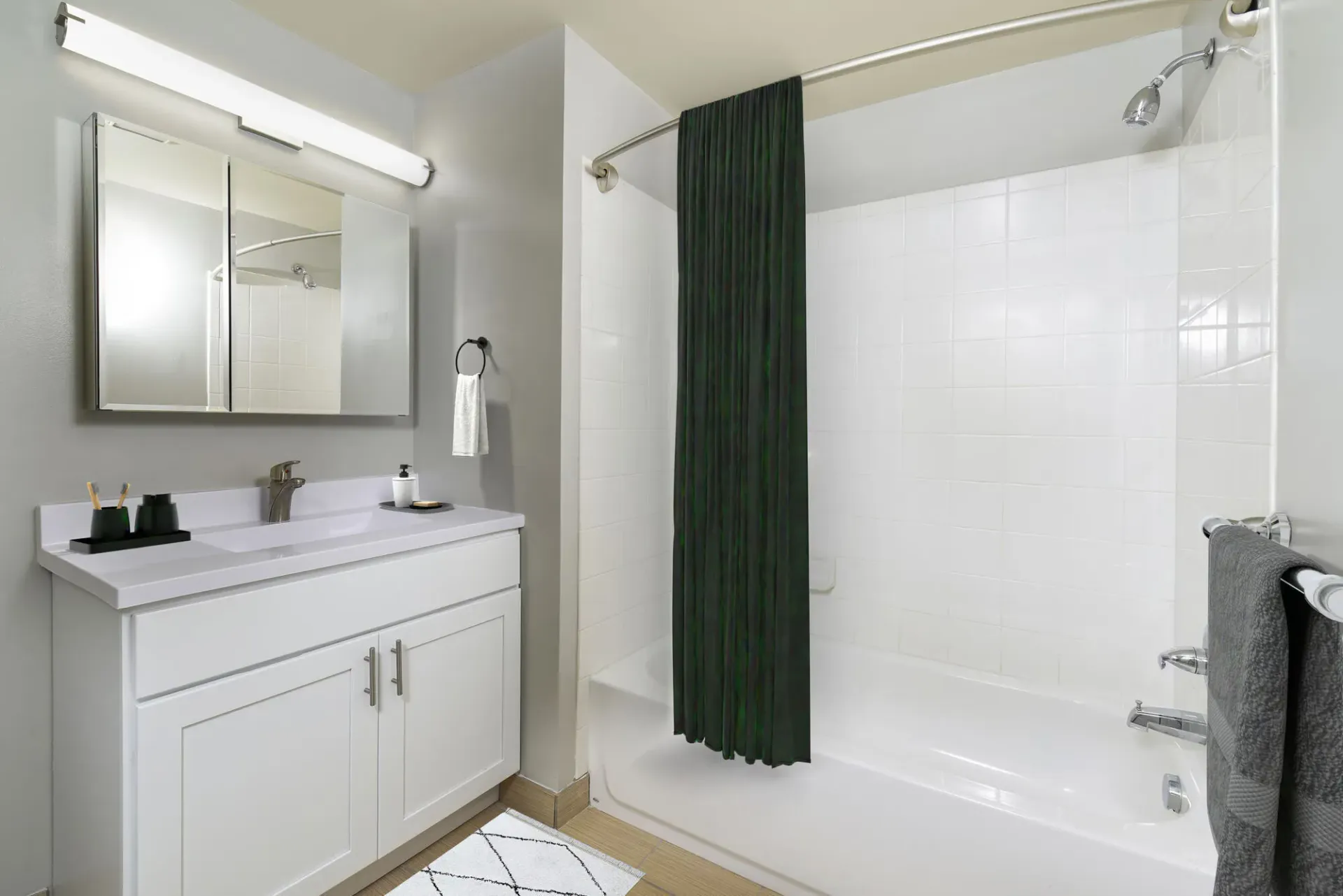 Bathroom with white vanity, mirror cabinet, and bathtub/shower with a dark green curtain.