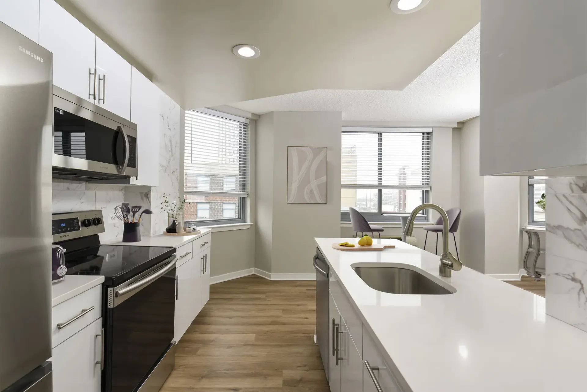 Modern apartment kitchen with white cabinets, stainless steel appliances, and an island sink.