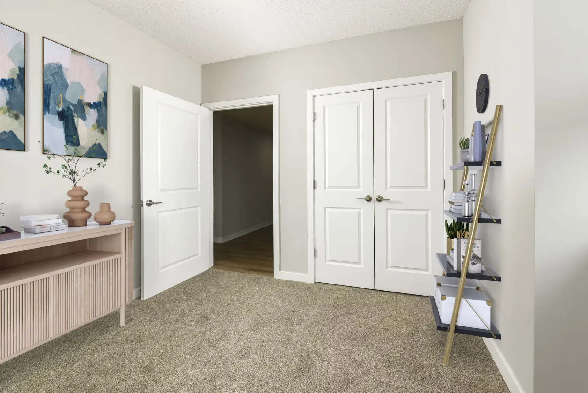 Interior living space with beige walls, double doors, and a ladder shelf with decor.