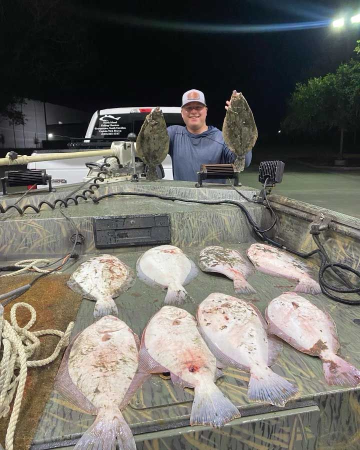 A man is standing in front of a boat holding two fish.