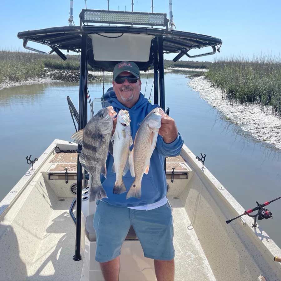 A man on a boat holding three fish in his hands