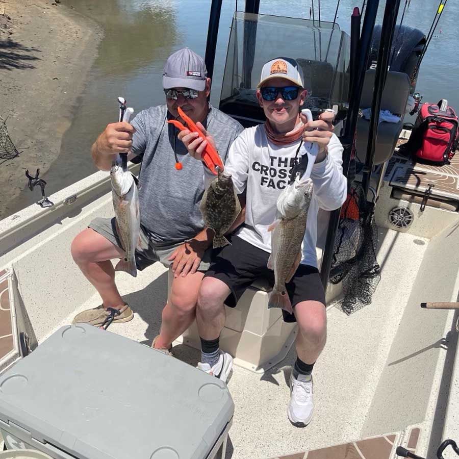 Two men are sitting on a boat holding fish.
