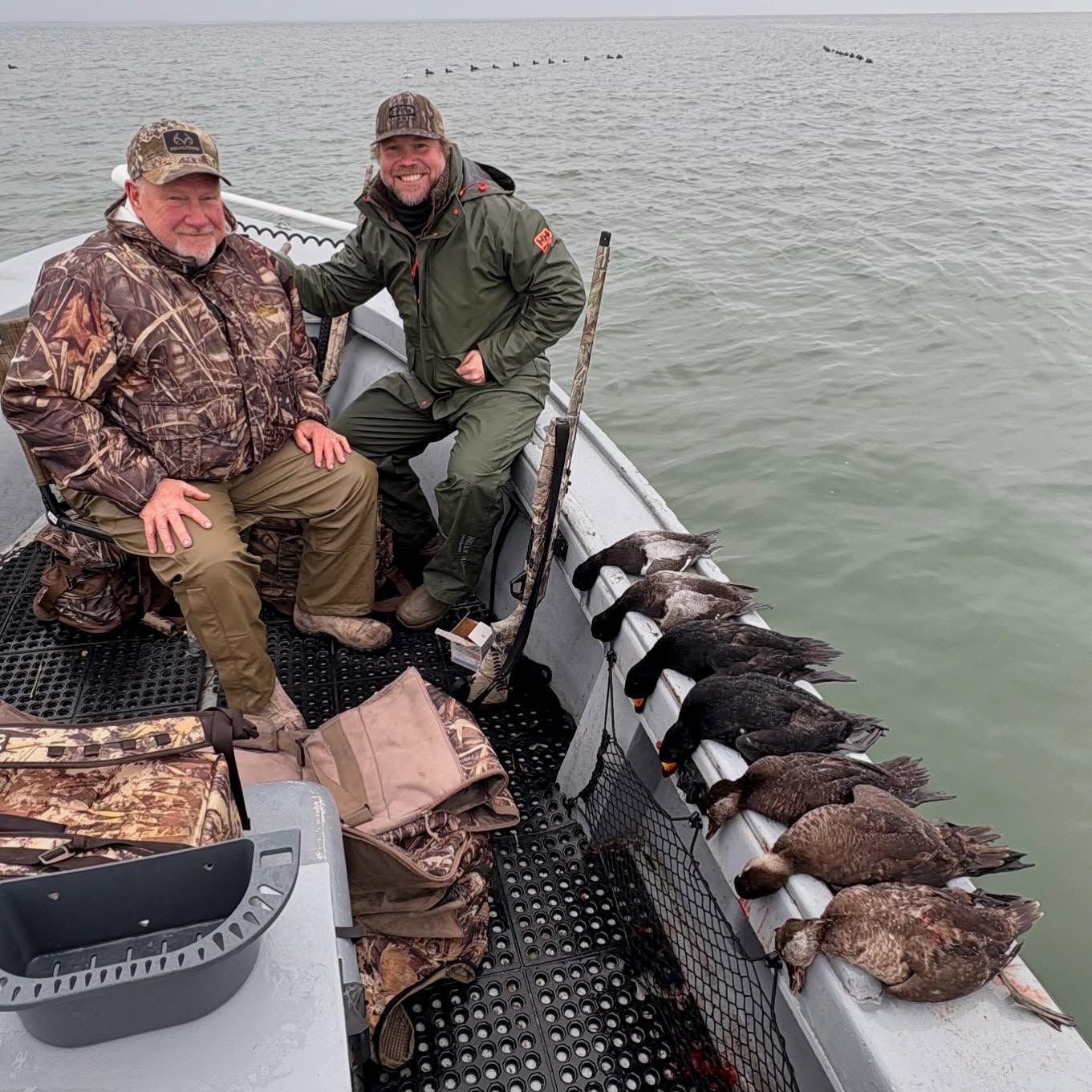 Two men are sitting on a boat with ducks on the side