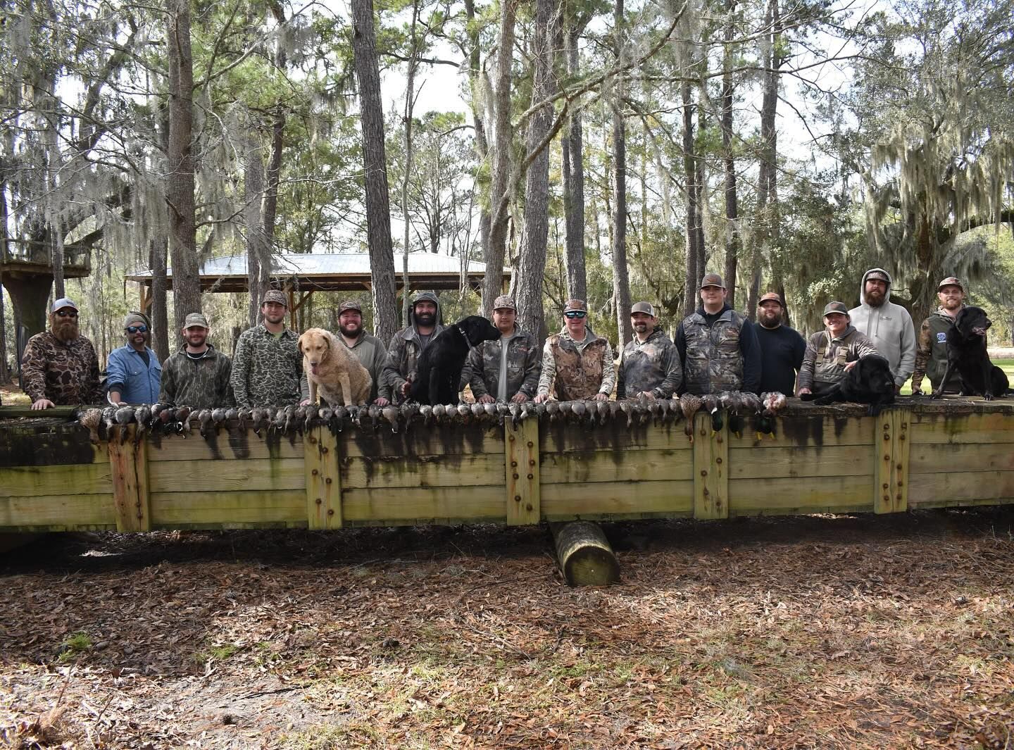 A group of soldiers and their dogs are posing for a picture in the woods.